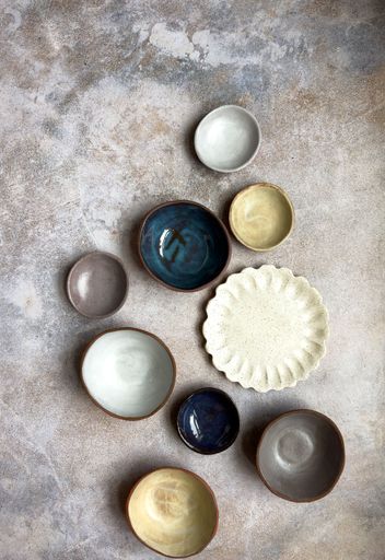 A selection of hand made ceramic bowls of different sizes and a petal plate