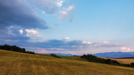 A scenic view of rolling hills and mountains seen from the top of a hill