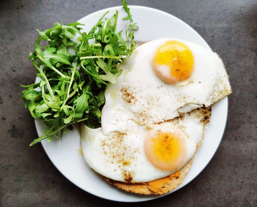 A top view of an omelet and greens served on a white plate