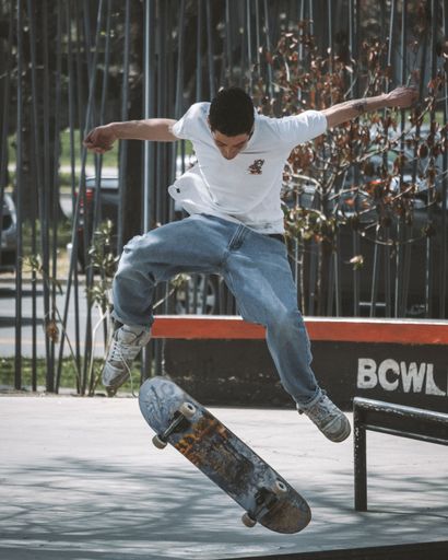 A young skateboarder jumps off a railing mid-air on a sunny day in the skatepark