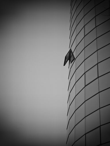A vertical greyscale shot of one open glass window on a modern building