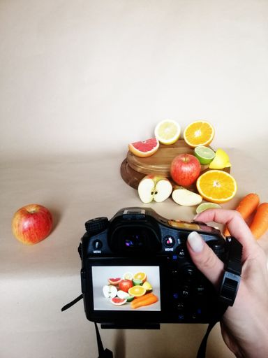A vertical shot of fruits and a camera in a studio on a white background