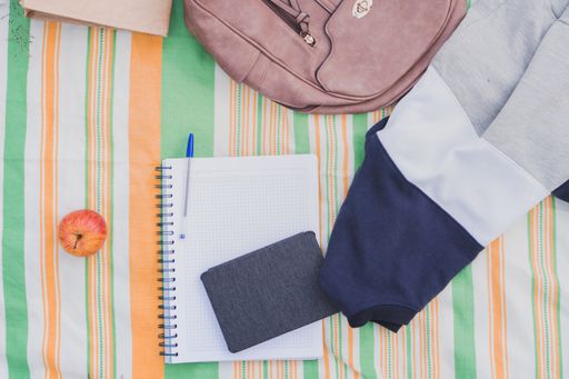 A top view of a backpack notebooks apple and pen