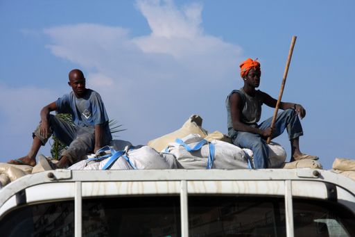 Two men riding on top of a truck to protect the shipment