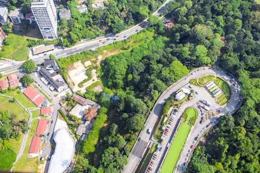 An aerial shot of a sprawling urban landscape featuring a cluster of buildings surrounded by lush green trees