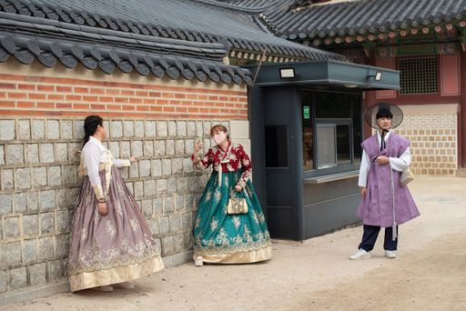 The women in traditional dresses take photos in front of the Gyeongbokgung Palace in Seoul, South Korea