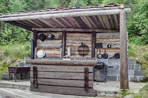 An aged wooden structure with a built-in outdoor kitchen providing a unique cooking experience in an open-air environment