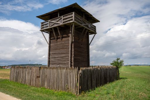 An elevated wooden watchtower stands tall on a lush green grass field