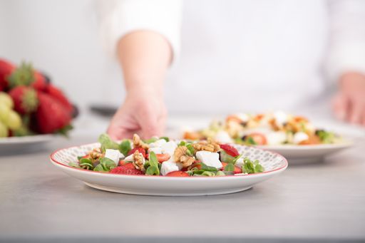 A Mediterranean diet salad with nuts, strawberries, cheese and lettuce.