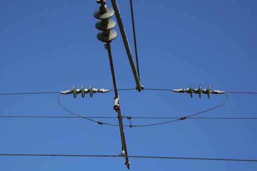 A low angle shot of transmission power lines under the sunlight and a blue sky