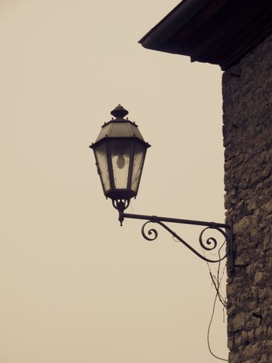 A closeup of a vintage wall-mounted lantern in the light background