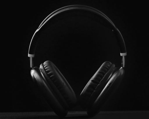 A black headphone isolated on a black background.