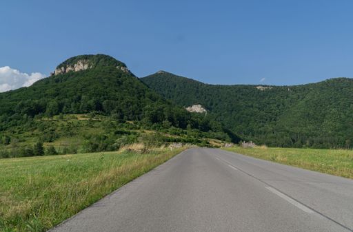 A scenic landscape view of a road to a rocky cliff over a lush green field in Cicmany, Slovakia