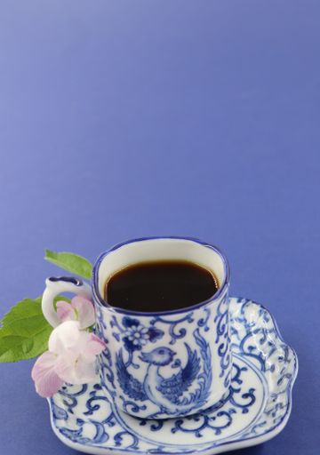 A closeup shot of a cup of black coffee on a blue surface