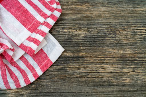 A top view of a red chequered towel on a wooden surface with space for text