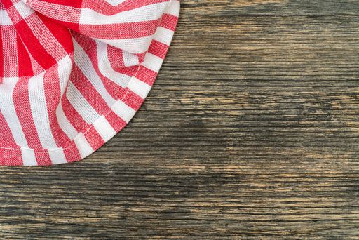 A top view of a red chequered towel on a wooden surface with space for text