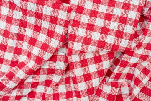 A top view of a red chequered kitchen towel on the table under the lights
