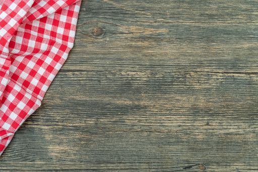 A top view of a red chequered towel on a wooden surface with space for text