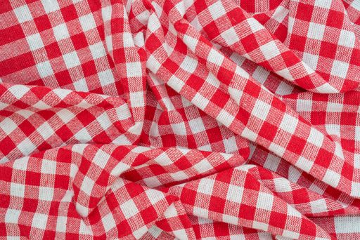 A top view of a red chequered kitchen towel on the table under the lights