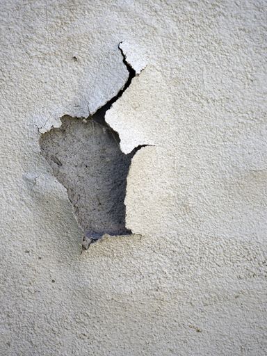 A vertical shot of cracked paint on the concrete wall