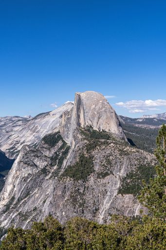 Vertical shot of the stunning Yosemite National Park on a sunny day, showcasing the majestic beauty of the landscape and its lush green foliage
