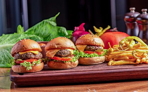A closeup of tasty Beef Sliders on a wooden cutting board under the natural light