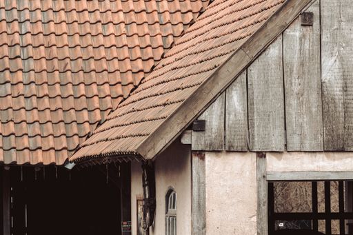 A closeup of an old wooden building with an old red roof at daytime