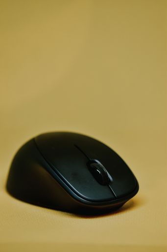 A closeup shot of a black wireless computer mouse on yellow background