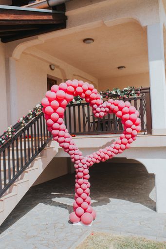 A vertical shot of a red big heart-shaped balloons ornament in a house yard