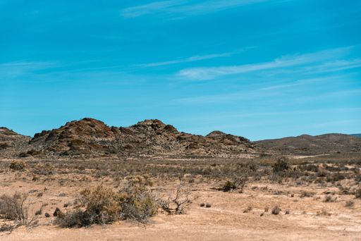 A scenic landscape featuring a dry valley and mountains under a blue sky in the Karoo, South Africa