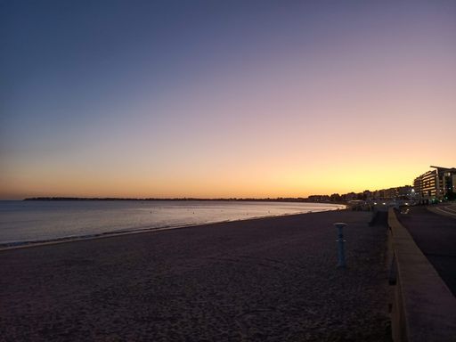 A stunning view of a cloudless night sky, illuminated in a deep, dark blue hue on the beach