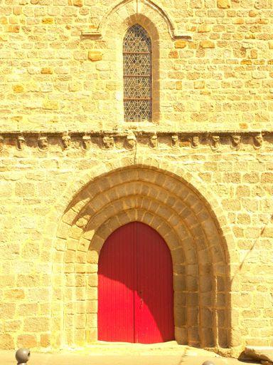 A vertical shot of an old brick stone wall with an archway and a red door