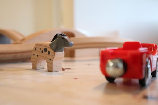 A closeup of a wooden toy horse on the table under the lights with a blurry background