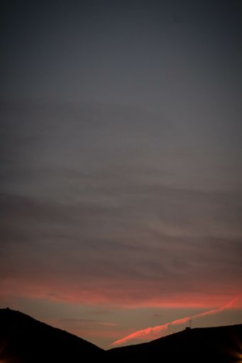 A vertical shot of fiery red sunset seen through a mountain silhouette - perfect for wallpapers