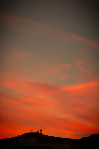 A vertical shot of fiery red sunset seen through a mountain silhouette - perfect for wallpapers