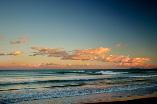 A closeup shot of beautiful sky colors with clouds over ocean waves during sunset
