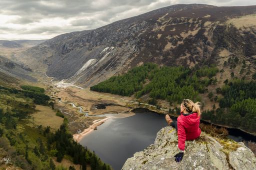 A woman traveler in a red jacket in the Spink Viewing Spot in Wicklow mountains national park, Ireland