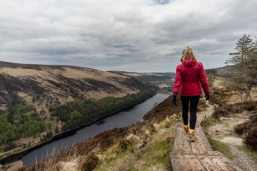 A woman traveler in a red jacket in the Spink Viewing Spot in Wicklow mountains national park, Ireland