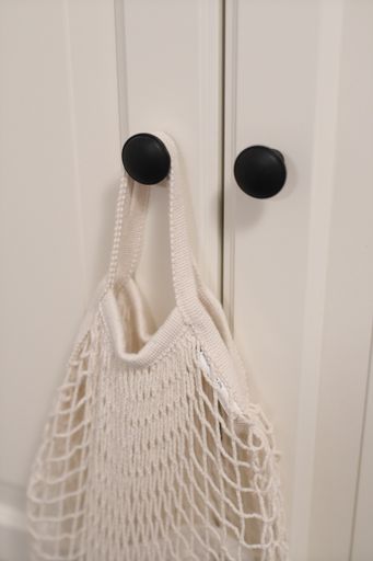A vertical picture of a net bag hanging from a closet under the lights