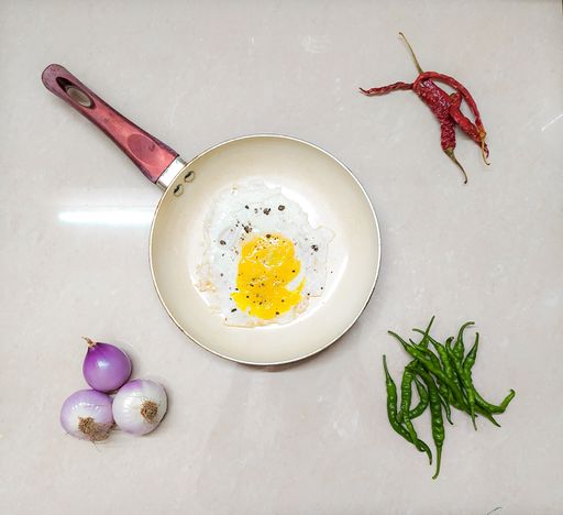 A top view of tasty scrambled eggs with spices and green peppers in a frying pan