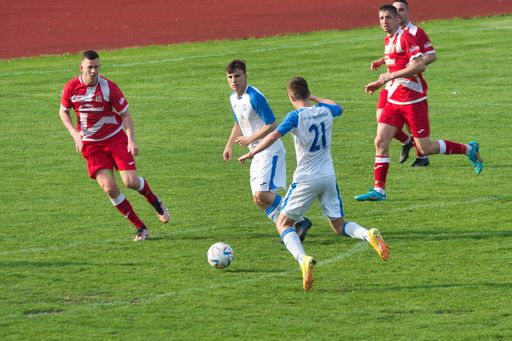 The male soccer players in uniform running on a grassy field in Prerov, Czech Republic