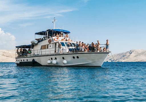 Boat carrying tourists on excursion around beautiful Pag island in adriatic sea in Croatia. Boat anchored near Beritnica beach.