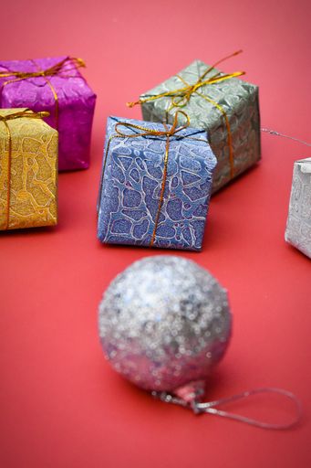 A closeup shot of a decorative ball and gift boxes on a red background