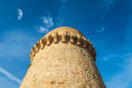 A low angle shot of the Torre de Piles on the Piles Beach under a blue sky and sunlight in Spain