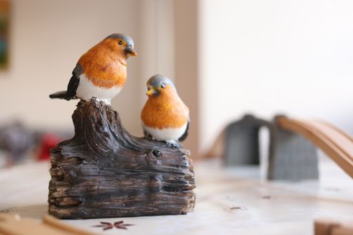 A closeup of two bird figures on a tree figure on the table under the lights with a blurry background