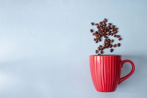 A top view of scattering coffee beans from a cup isolated on a gray background