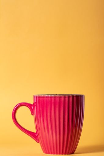 A vertical shot of a cup of hot coffee isolated on a yellow background