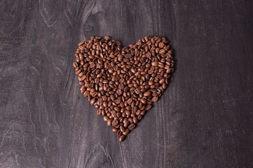 A top view of roasted heart-shaped coffee beans on a wooden table