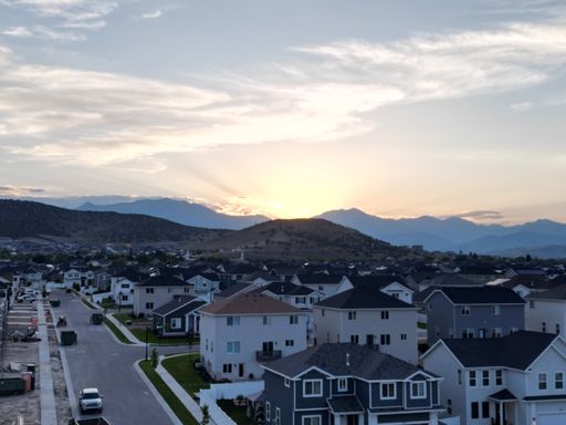 A scenic view of a residential street lined with houses and leading to a mountain backdrop