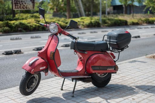 A typical Italian city motorcycle, the red Vespa P 200 E in the city